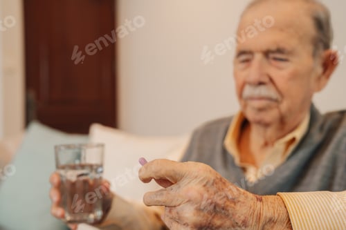 Preview: Old man holding a glass of water taking a pill