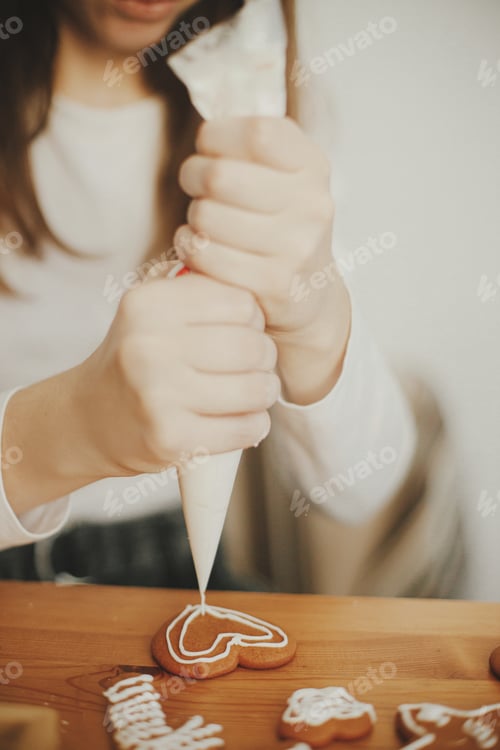 Preview: Woman hands decorating christmas gingerbread cookie with icing, close up. Xmas holiday preparations