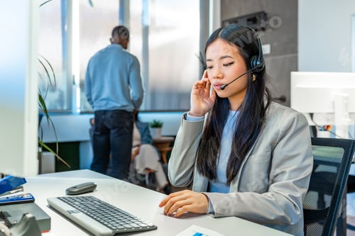 Preview: Asian businesswoman wearing headset working in modern coworking office