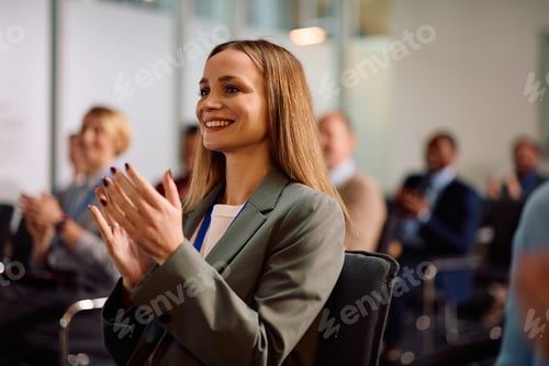 Preview: Happy female entrepreneur applauding on business seminar at conference hall.