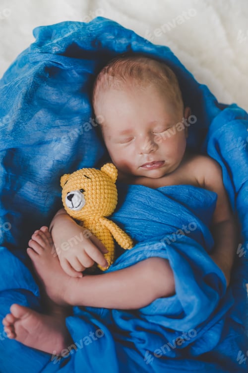 Preview: A newborn baby sleeps with a teddy bear. Selective focus.