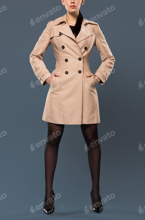 Preview: Slim woman in black pantyhose and beige trench on dark background