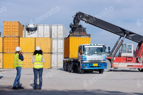 Preview: Two engineers in safety vests supervise container loading at a shipping yard.