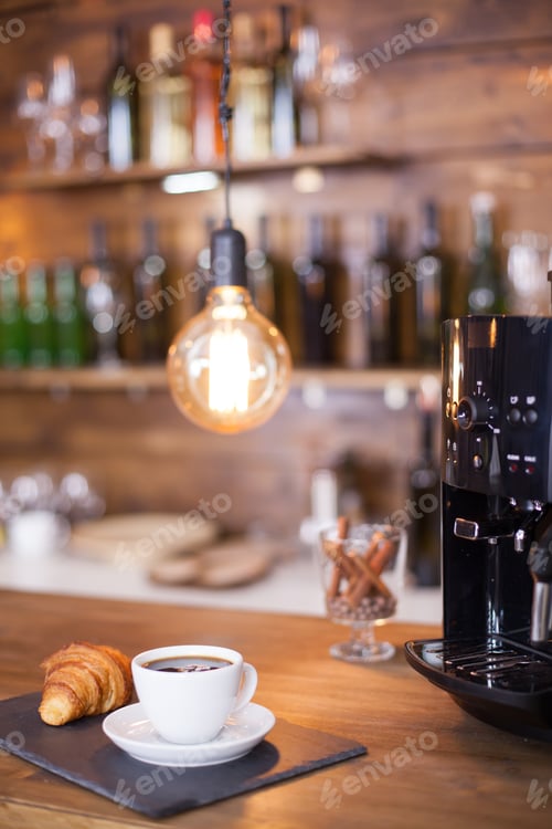 Preview: Modern coffee machine next to a cup of esoresso coffee on wooden counter bar