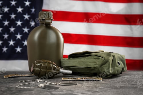 Preview: Military canteen, first-aid kit and grenade on table against American flag background