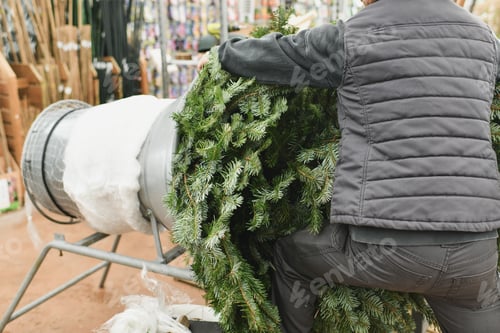 Preview: Salesman being wrapped up a Christmas tree packed in a plastic net