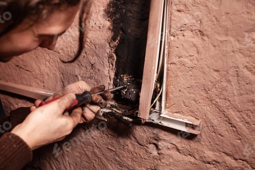 Preview: A man fixes a burnt socket. Short circuit, burnt wires. traces of smoke fire on the wall. The