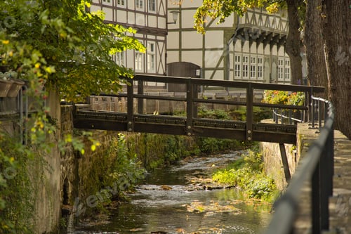 Preview: Narrow bridge in front of a picturesque house on the banks of a tranquil river