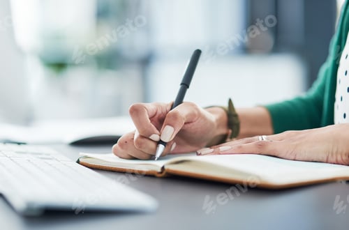 Preview: Cropped shot of a businesswoman writing in a notebook at her desk in a modern office