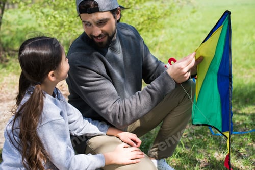Preview: father and daughter sitting with kite on meadow