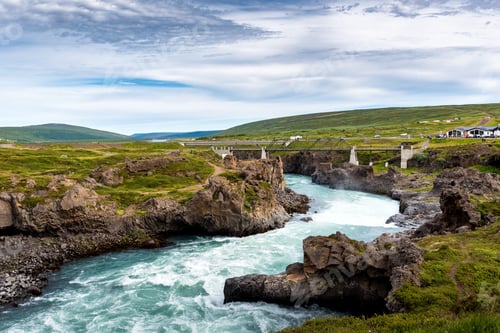 Preview: A river from Godafoss Falls, Akureyri, Iceland, surrounded by huge rocks and a concrete bridge