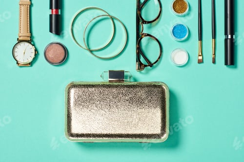 Preview: Top view of watch, lipstick, bracelets, glasses, eyeshadow, blush, clutch, cosmetic brushes and