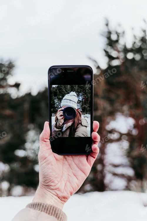Preview: woman taking picture to mobile phone, selfie. Techonolgy and lifestyle. Snowy mountain background