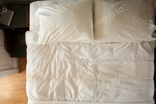 Preview: Top view of an unmade bed with white bedding