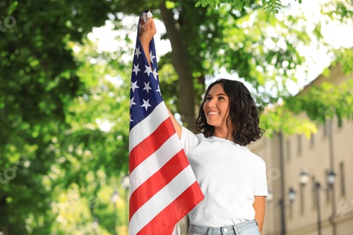 Preview: Happy young woman with American flag on sunny day
