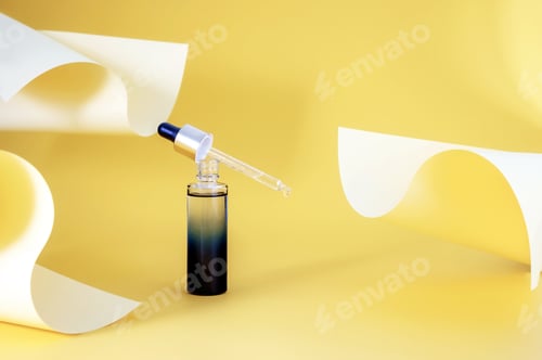 Preview: bottle with an essential oil pipette on an abstract background made of colored yellow paper
