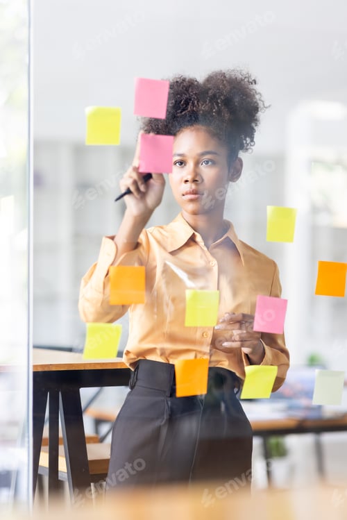 Preview: Young Serious african american Creative team use post it notes to share idea sticky note on glass