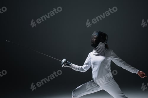 Preview: Fencer in fencing mask exercising on black background