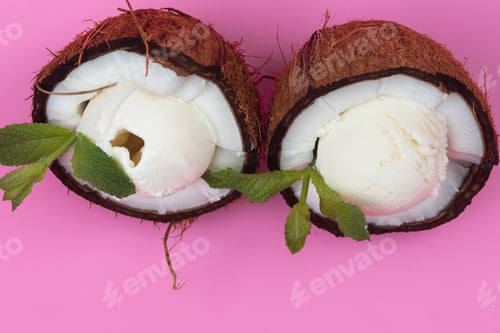Preview: Vanilla ice cream balls in fresh coconut halves decorated with mint leaves on a pink background