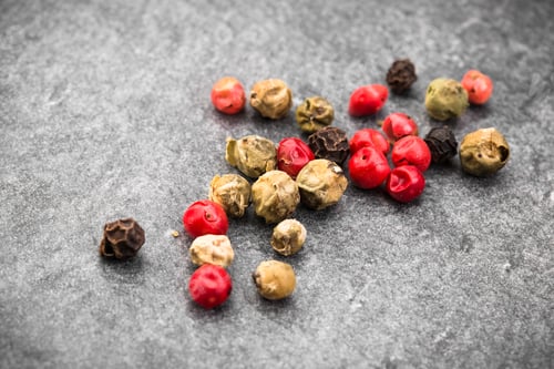 Preview: Peppercorns over black stone background. Top view.