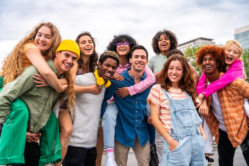 Preview: Happy playful multiethnic group of young friends bonding outdoors