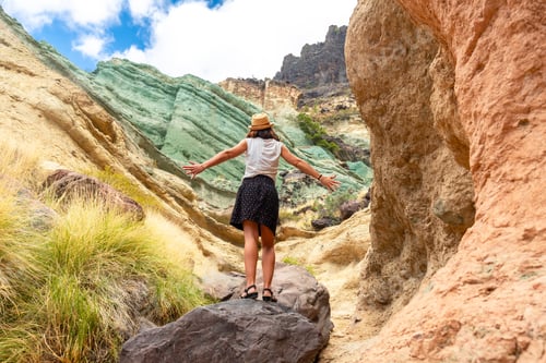 Preview: A tourist woman with a hat at the Azulejos de Veneguera or Rainbow Rocks in Mogan, Gran Canaria