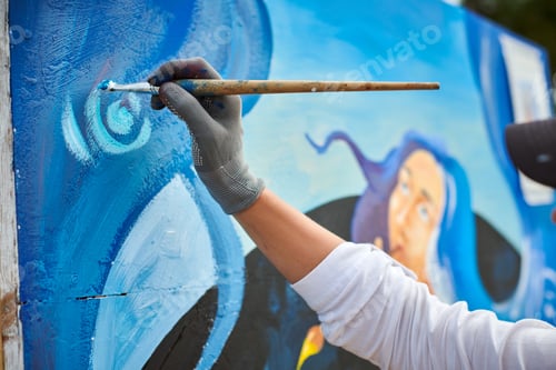 Visualização: A mão de uma artista feminina aplica pequenas pinceladas de tinta com pincel na tela, criando uma imagem