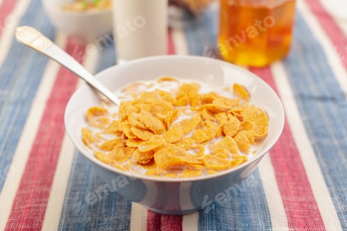 Preview: Cereal with milk sits in a bowl on a striped tablecloth during breakfast time