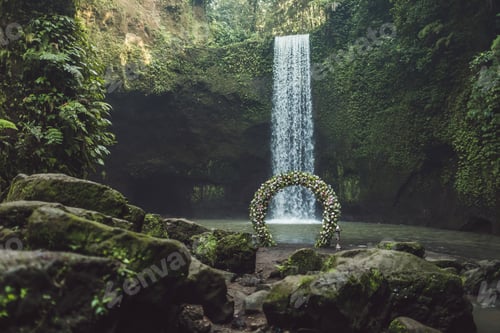 Preview: Wedding ceremony on Tibumana waterfall, Bali. Round arch with fresh flowers in jungle.