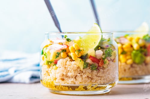 Preview: Vegan salad with vegetables and quinoa in glass jars, blue background.