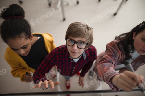 Preview: Top view of students writing at board in school class.