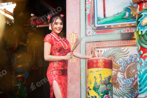 Preview: Chinese New Year, Chinese woman in red cheongsam dress holding incense pay at shrine.