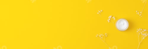 Preview: Jar of cosmetic cream with flowers on yellow background. Flat lay, copy space