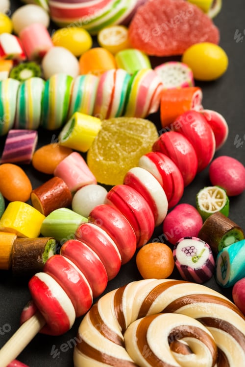 Preview: close up view of bright swirl lollipops among fruit caramel multicolored candies