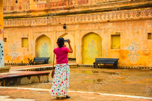 Preview: Woman tourist taking a photo of the Amer fort, located in Jaipur, India.