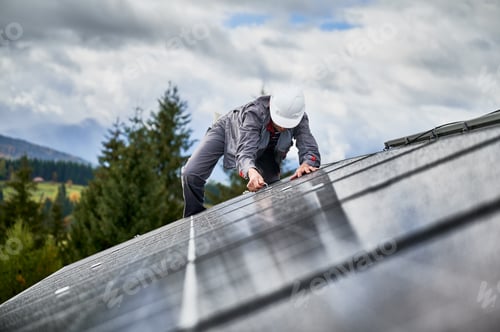 Preview: Man technician mounting photovoltaic solar panels on roof of house with help of hex key.