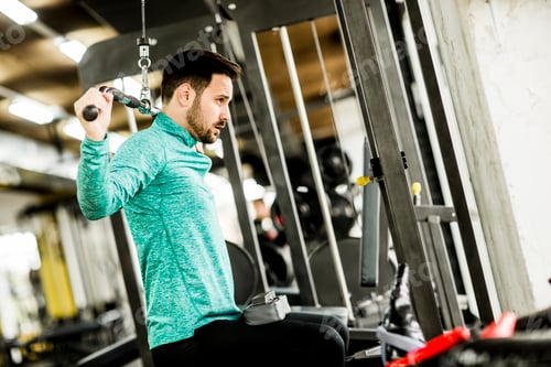 Preview: Young man doing exercise for triceps in the gym on mashine