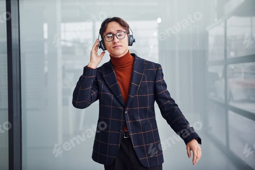 Preview: Listening to the music in headphones. Young business man in luxury suit and formal clothes