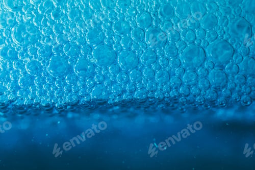 Preview: Closeup of blue translucent soap bubbles floating on the water surface, perfect for backgrounds