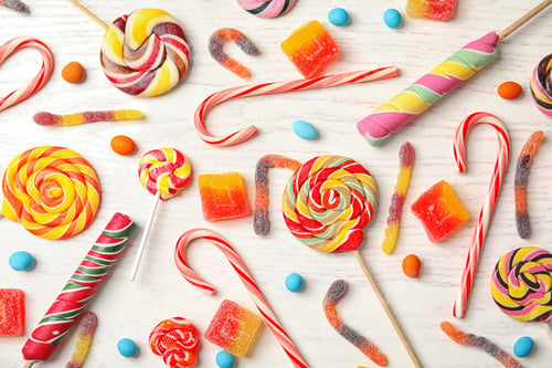 Preview: Many different yummy candies on white wooden background, top view
