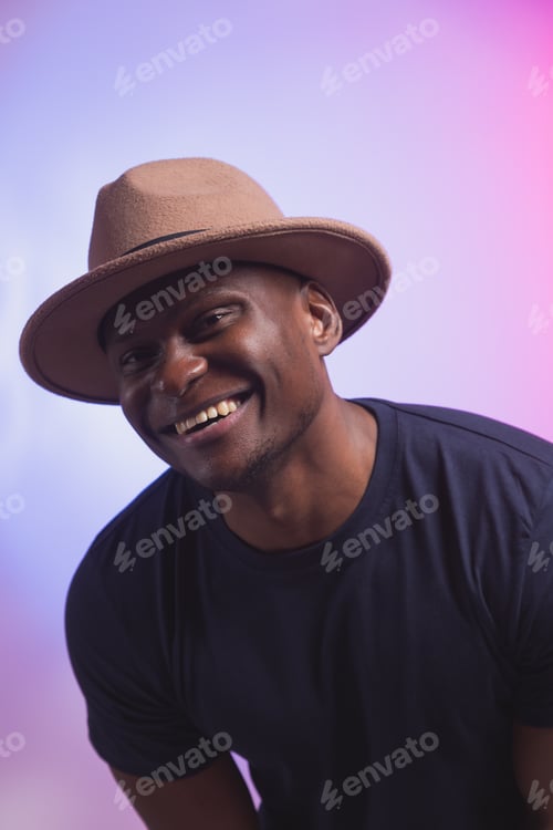 Preview: Smiling happy american african man wear stylish hat on pink and purple background. Festive and party