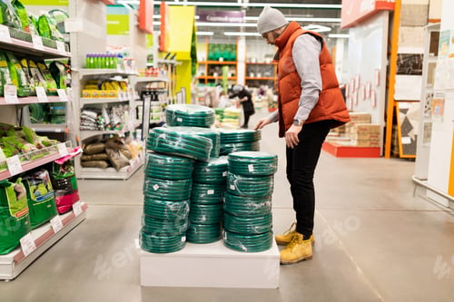 Preview: a man in a garden hypermarket is selected Come on a hose for watering work