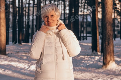 Preview: Portrait of a happy middle-aged woman in winter in a snowy city park at sunset time. Winter vacation