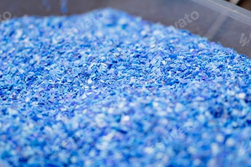 Preview: Close-up shot of shredded plastic caps stored in a special container at waste recycling station