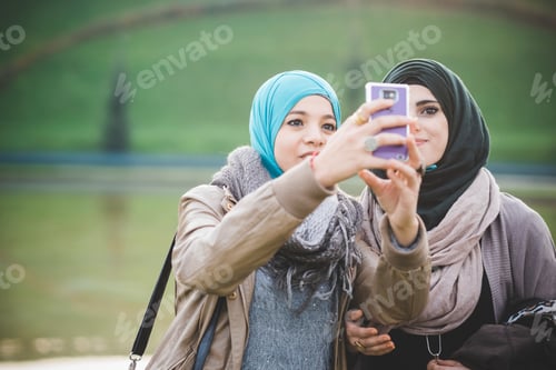 Preview: Two female friends at lakeside taking smartphone selfie