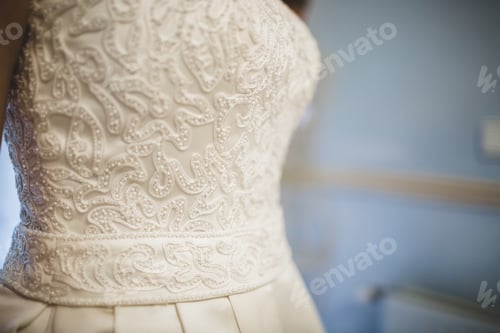 Preview: Detail of a white wedding dress hanging.