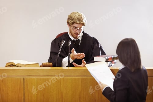 Preview: Present your case...Serious young judge sitting in the courtroom with a stern facial expression.