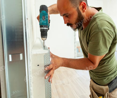 Preview: Construction worker installing metal corner bead on drywall with cordless screwdriver