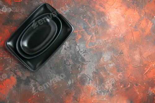 Preview: top view black oval and rectangular platters on dark red background with free place