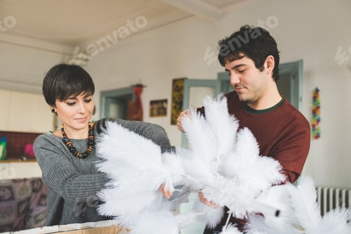 Preview: Young couple at home decorating xmas tree